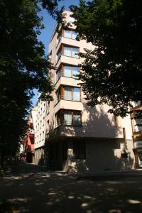 ein hohes weißes Gebäude auf einer Straße mit Bäumen in der Unterkunft Lazensky Hotel Park in Poděbrady