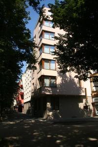 a tall white building on a street with trees at Lazensky Hotel Park in Poděbrady