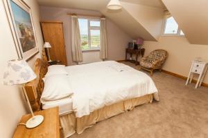 a bedroom with a large white bed and a chair at Sunville Bed And Breakfast in Ballycotton