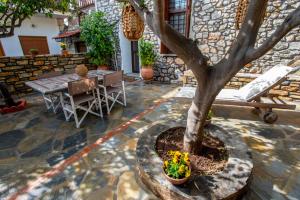 un patio de piedra con una mesa y un árbol en The Backyard Fisherman's House, en Kato Gatzea