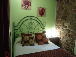 Dormitorio verde con cama con almohadas en Casa Rural A Eira Vella en Padrón
