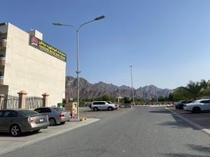 a parking lot with parked cars and mountains in the background at Concord Beach House in Dibba