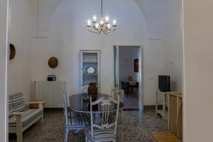 een eetkamer met een tafel en stoelen en een kroonluchter bij Casa Alba & Francesco in Specchia Gallone
