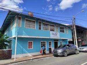 um edifício azul com uma mulher a andar em frente dele em La Casa de Doña Cata em Bajo Boquete