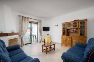 a living room with two blue chairs and a table at Apartamento T1 Carvoeiro c/piscina e a 300m Praia in Carvoeiro