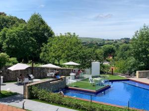 a swimming pool with tables and umbrellas next to at Hotel Marfrei in Hinojedo