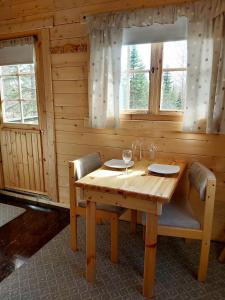 a wooden table and chairs in a room with windows at Bakkakot 3 Cozy Cabin In The Woods in Akureyri