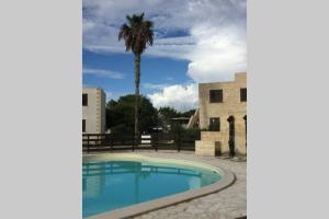 un palmier et une piscine en face d'un bâtiment dans l'établissement Vacanze isolane, à Favignana