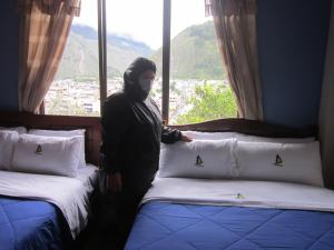 una persona con una máscara de pie junto a dos camas en Hosteria Llanovientos, en Baños