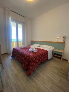 Habitación de hotel con cama con colcha roja en Hotel Artide, en Rímini
