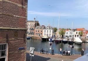 a group of people sitting on benches next to a river with boats at Hartje Goes! in Goes