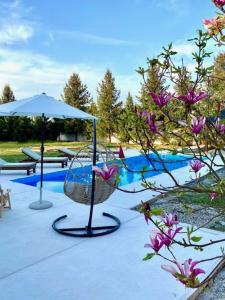 a pool with a swing and an umbrella and flowers at LA CASITA Serbia in Surčin