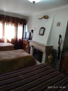 a bedroom with two beds and a fireplace at Quartos Cesário Verde Massamá in Queluz