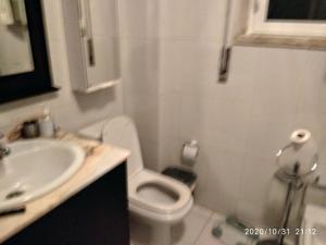 uma casa de banho com um WC branco e um lavatório. em Quartos Cesário Verde Massamá em Queluz