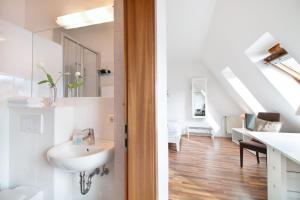 een witte badkamer met een wastafel en een trap bij fewo1846 - Strandresidenz Wassersleben Lee - strandnahes Studioapartment im Dachgeschoss in Harrislee
