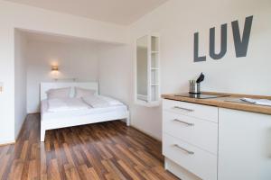 Schlafzimmer mit einem weißen Bett und Holzboden in der Unterkunft fewo1846 Strandresidenz Wassersleben - Luv - komfortables Studio-Apartment mit Balkon und Meerblick in Harrislee