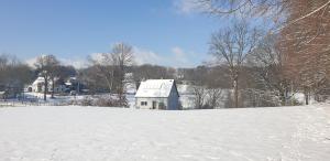 un campo cubierto de nieve con una casa en el fondo en Souterrainwohnung im Grünen, en Witten
