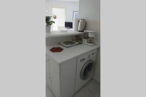 een wasruimte met een wasmachine en droger bij T2 climatisé à 5 minutes à pied de la plage avec parking, piscine et wifi in Fréjus