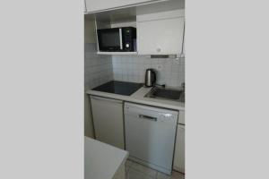 a small kitchen with a sink and a microwave at T2 climatisé à 5 minutes à pied de la plage avec parking, piscine et wifi in Fréjus
