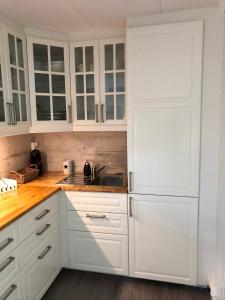 a white kitchen with white cabinets and a sink at Koselig maritim leilighet sentralt i Stavern in Stavern