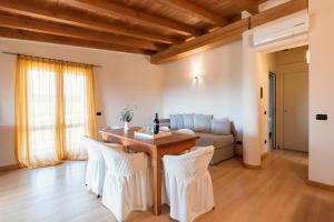 sala de estar con mesa de madera y sillas blancas en Agriturismo Podere L'Agave, en San Vincenzo