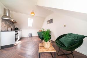 a living room with two green chairs and a table at Dierenweide Upstairs in Goedereede