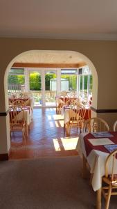 un comedor con mesas, sillas y ventanas en Riverwalk House B&B, en Oughterard