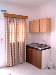 eine Küche mit Spüle und einem Fenster mit Vorhängen in der Unterkunft Scarpantos in Amoopi