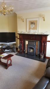 a living room with a fireplace and a television at Riverwalk House B&B in Oughterard