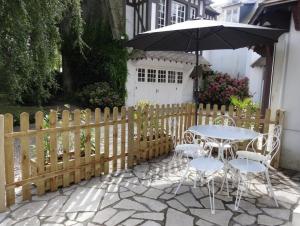 uma mesa e cadeiras com um guarda-sol ao lado de uma cerca em Le Petit Marais em Isigny-sur-Mer