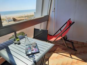 une table avec une bouteille et une chaise sur un balcon dans l'établissement Vue superbe sur l'océan, studio et stationnement, à Saint-Jean-de-Monts