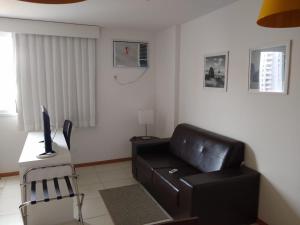 een woonkamer met een zwarte leren bank en een bureau bij Flat Constelações in Campos dos Goytacazes