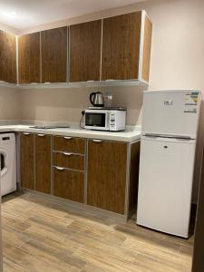 a kitchen with a white refrigerator and a microwave at Hosta Hotel Suites in Riyadh