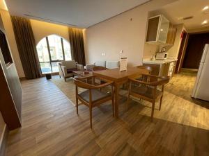 Hosta Hotel Suites في الرياض: مطبخ وغرفة معيشة مع طاولة وكراسي