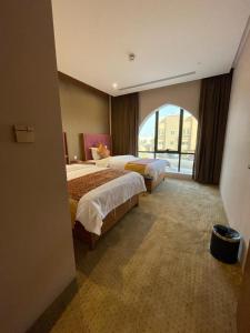 a hotel room with two beds and a large window at Hosta Hotel Suites in Riyadh