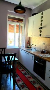 a kitchen with white cabinets and a table and a sink at Louis Appartment in Orikum