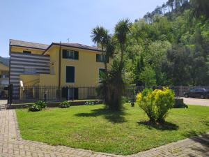 a yellow house with two palm trees in a yard at Marino Apartments in Levanto