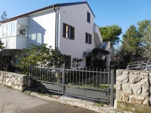 a white house with a fence in front of it at Apartments Milenka in Punat
