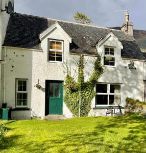 a white house with a green door on a yard at Inverlael Farm Cottages in Inverlael