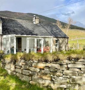 una antigua casa de piedra con una pared de piedra en Inverlael Farm Cottages en Inverlael