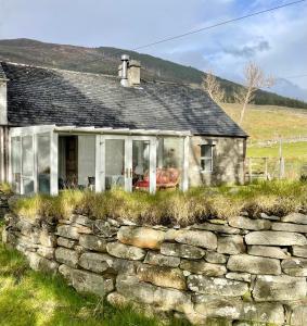 ein altes Steinhaus mit einer Steinmauer in der Unterkunft Inverlael Farm Cottages in Inverlael