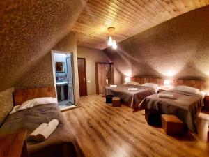 a bedroom with three beds in a room with wooden floors at Kazbegi Inn in Stepantsminda