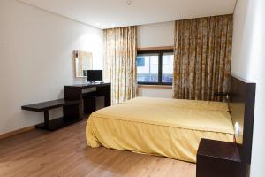 ein Hotelzimmer mit einem Bett, einem Schreibtisch und einem Fenster in der Unterkunft Mondim AL & Spa in Mondim de Basto