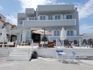 ein Gebäude mit Stühlen und Sonnenschirmen davor in der Unterkunft Hotel Elafonisos in Elafonisos