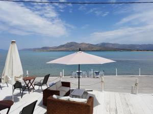 a patio with chairs and an umbrella and the water at Hotel Elafonisos in Elafonisos