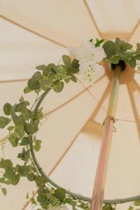 un vase avec des fleurs blanches assises au-dessus d'un parasol dans l'établissement Duneden Belle Glamping, à Randalstown