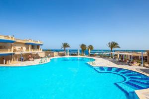 a swimming pool with the ocean in the background at King Tut Aqua Park Beach Resort in Hurghada