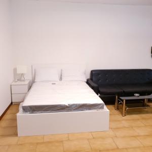 a bedroom with a white bed and a black couch at Hotel Paradiso Dépendance in Altedo