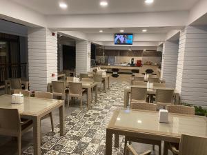 a restaurant with tables and chairs and a flat screen tv at MİYAS LUXURY HOTEL in Kemer