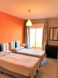 dwa łóżka w pokoju z pomarańczowymi ścianami w obiekcie Precioso apartamento frente al mar Benalbeach w mieście Benalmádena
